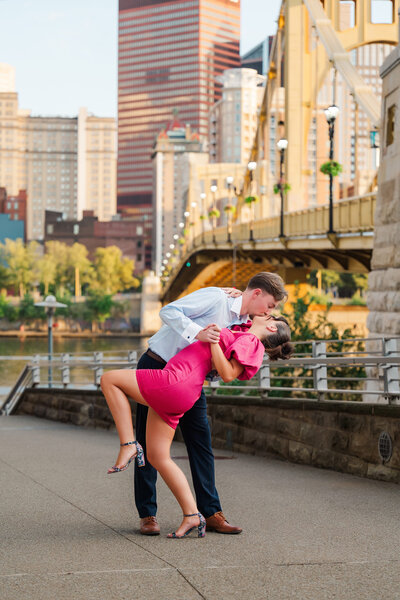 couple posing for photos after they got engaged with the pittsburgh yellow bridges behind them