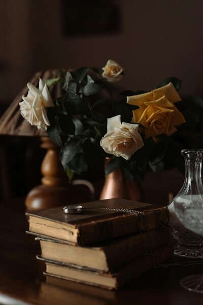 Stack of historic leather-bound books and a vase of flowers on a table, symbolizing expert copy editing and proofreading services for authors and publishers.