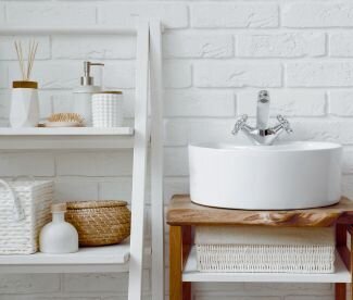 bathroom organization with toiletries placed on a ladder shelf next to the sink in front of a brick wall