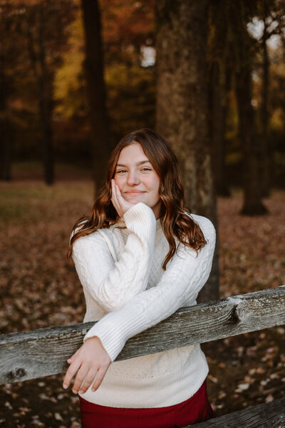 A high school senior strikes a confident pose over a modern fence in Northeast Ohio, showcasing their unique style in this urban-inspired senior portrait session. With the cityscape or suburban backdrop, this outdoor photo captures the senior’s individuality and youthful spirit, making it the perfect choice for students seeking dynamic and personalized senior photos in Northeast Ohio.