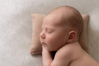 Baby boy sleeping on a tan pillow, close up profile image