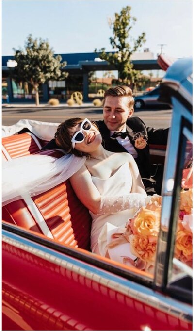 Newlyweds sitting in a vintage car wearing retro style attire