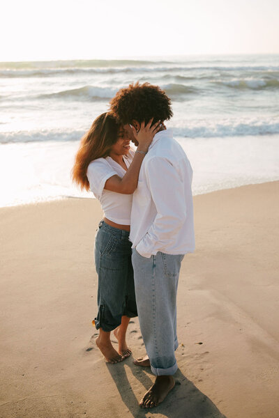 Engaged couple embracing on the beach in San Diego