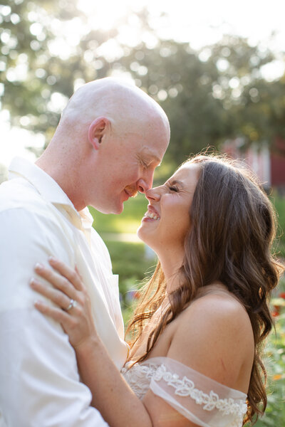 Bride and groom smile at each other with their eyes closed while their noses touch