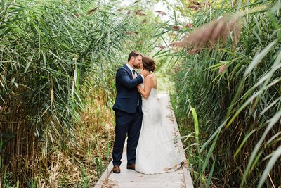 Wedding couple shares a kiss on the bridge at the Ruscom Shores Conservation Area