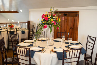A table decorate for a corporate event at Hidden Hill. There is a large floral arrangement in the center of the table.