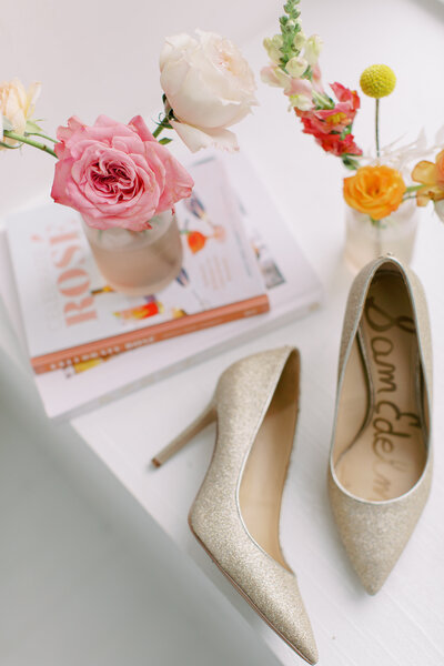 Gold glitter Sam Edelman pumps laying next to coffee table books and bud vases