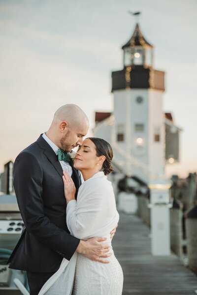 bride and groom looks lovingly at eachother in a gentle embrace on a dock in Saybrook Point Marina Thr bride grins at hte groom while the groom looks back Love Jackie Weddings CT Wedding Photographer
