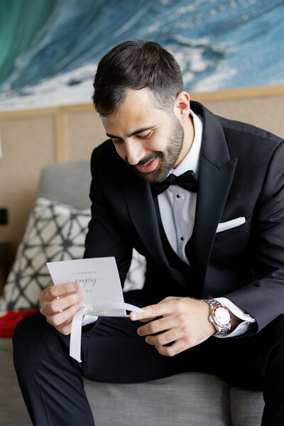 A person in a suit smiling and reading a letter 