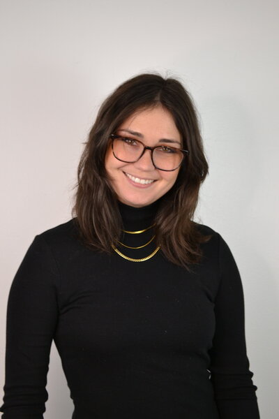Jessica wearing a white blazer, smiling as she writes in her planner