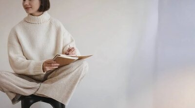 Kvinna i stickad tröja skriver i anteckningsbok – övning för att hantera medberoende i praktiken.