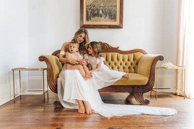 A mother siting on a yellow coach with her baby son and daughter. Photographed by Casey McMurray Photography