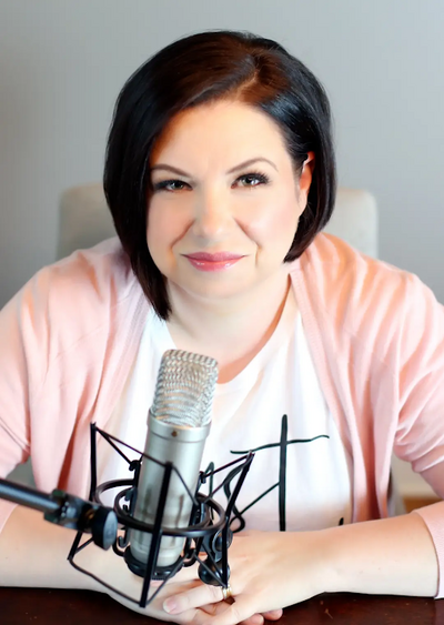 Jessica wearing a white blazer, smiling as she writes in her planner