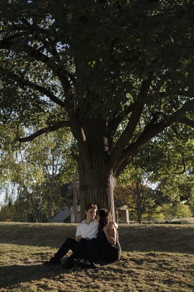couple sitting against a tree