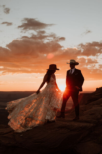 bride and groom standing in the desert at sundown