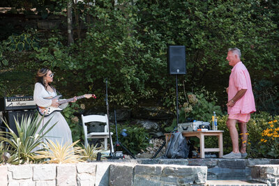 Youn woman playing guitar with her sunglasses during a casual garden celeration