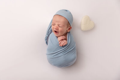 baby wrapped in blue yawning by Newborn Photography Bucks County PA