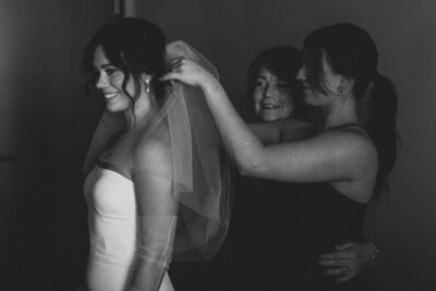 mom and sister helping bride with her veil