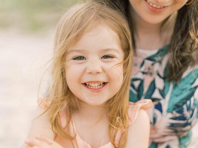 little girl smiling big on the beach with momBy Carrie Pellerin