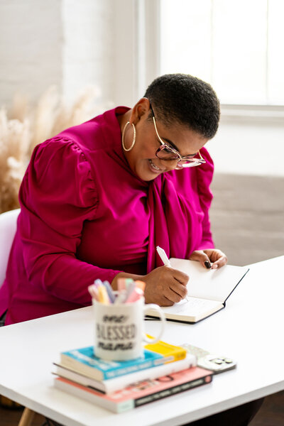 A woman professional writing in her agenda, reflecting personal growth and planning her career development. She is focused and organized, symbolizing empowerment and progress for women professionals.