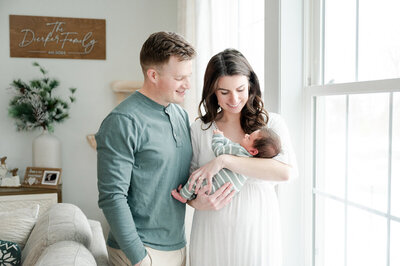 Mom and dad holding baby in the nursery.