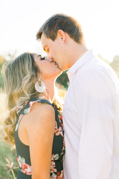Two people kissing at golden hour in a field in Houston, Texas