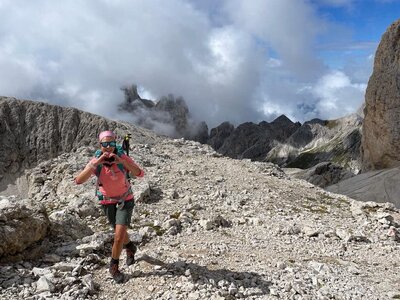 Moderatorin Hanna Zöller beim Wandern in den Alpen, mit Rucksack und Sportkleidung auf felsigem Bergpfad