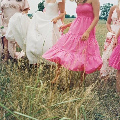 Bride with bridesmaids walking through field by wedding film photographer Noble Photo Co
