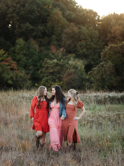 mother and two daughters in pink dresses walking in park for family photos