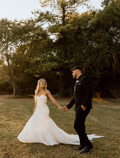 Outdoor wedding ceremony at a white barn venue in Wyoming, with a couple exchanging vows under the open sky, creating a rustic and romantic atmosphere