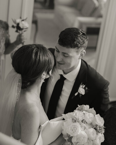 a black and white image of bride and groom smiling at each other after just getting married