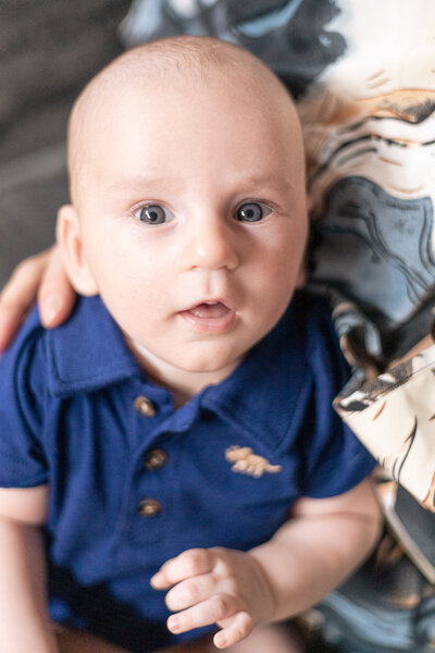 Newborn baby on mom's lap looking at the camera.