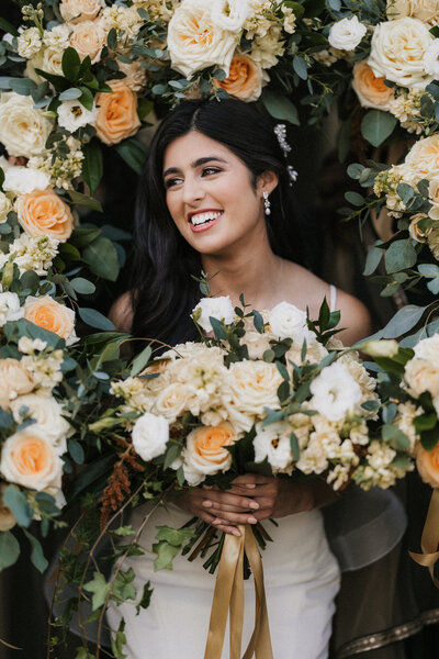 a bride smiling while surrounded by flowers