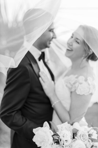 A bride and groom share a moment beneath a veil.