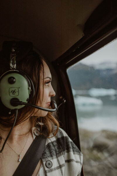 Bride looks out helicopter window during Alaska elopement