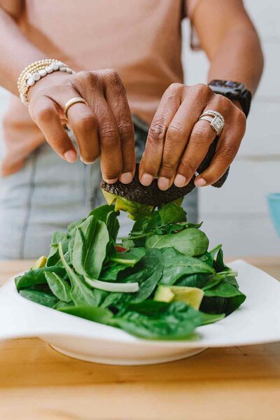 Woman wearing rings putting leady greens on a plate.
