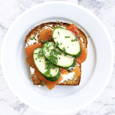 A top shot of a toast with salmon and vegetables over it.