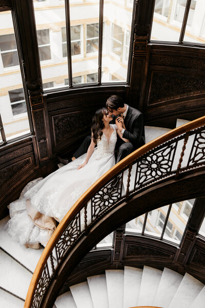 a wedding couple cuddles on the iconic Rookery stairs in Chicago