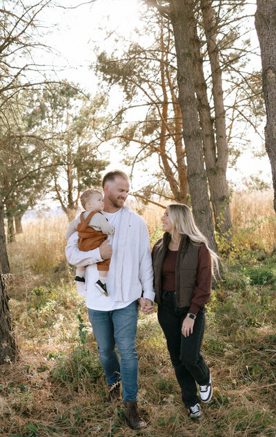Expecting couple sharing a tender kiss in front of a rustic wooden fence during golden hour in Idaho