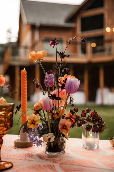 Colorful but moody wedding centerpiece with purple & orange flowers and mushrooms!