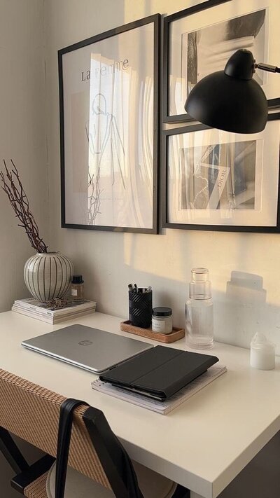 A warm, minimalist home office setup with a laptop, tablet, and modern decor on a white desk, bathed in soft natural light

