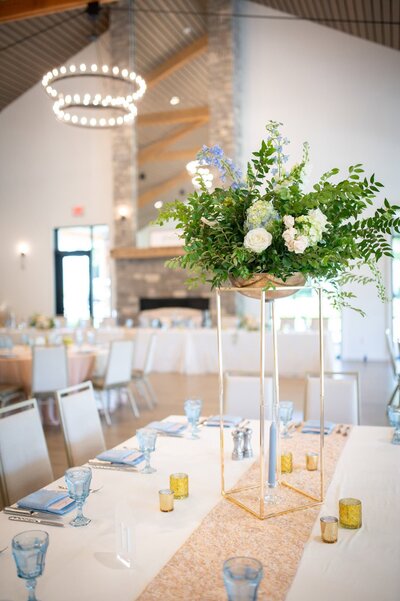 floral arrangement on table at wedding reception with round light fixture in the backdround
