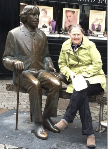 Christine Riley, founder of Wryly Edits, sitting beside the Oscar Wilde statue in Galway, Ireland, highlighting her passion for literature and editing.