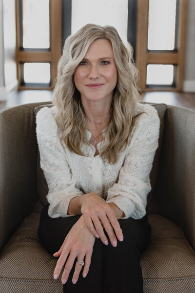 Kristin Tibbs seated in a neutral-toned room, wearing a cream sweater, offering a welcoming and professional presence.