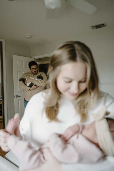 Newborn baby swaddled and sleeping peacefully during an in-home lifestyle session and a cat in the background