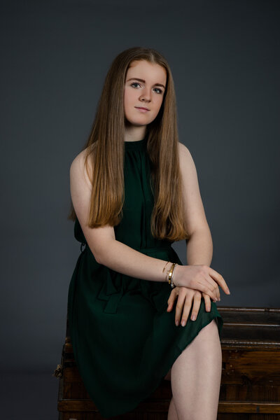 A teenage girl sitting down in a green dress