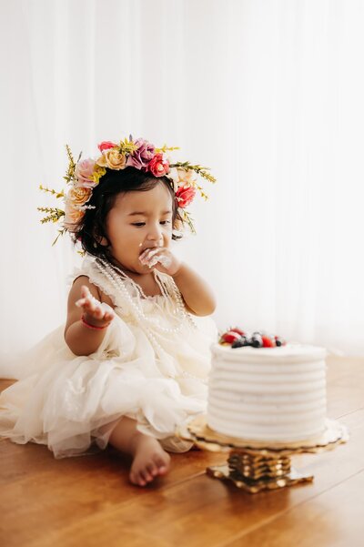 toddler smiling at camera in rose colored dress with flower crown