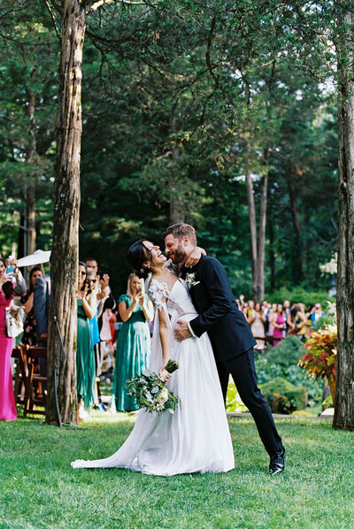 Bride smiling over her shoulder while holding a lush pink and white bouquet in the stone streets of Altos de Chavón — captured by Asia Pimentel Photography.