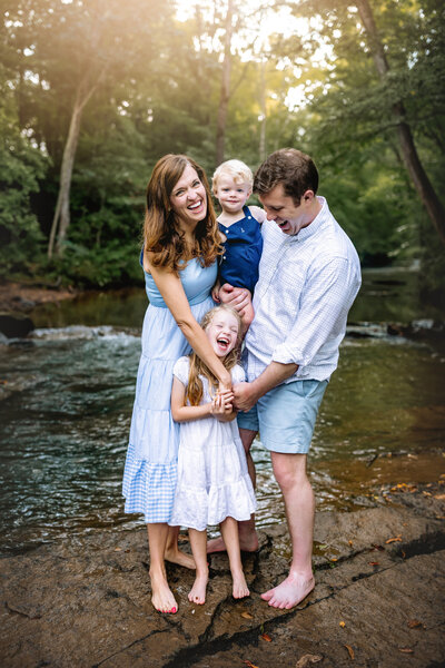 Family laughs together during a  family photoshoot at a creek near Birmingham