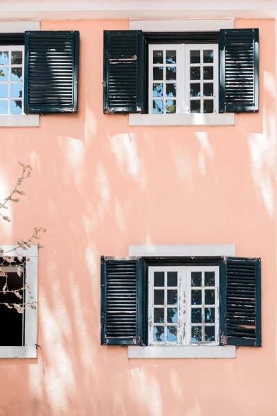 Exterior de casa naranja con persianas abiertas.